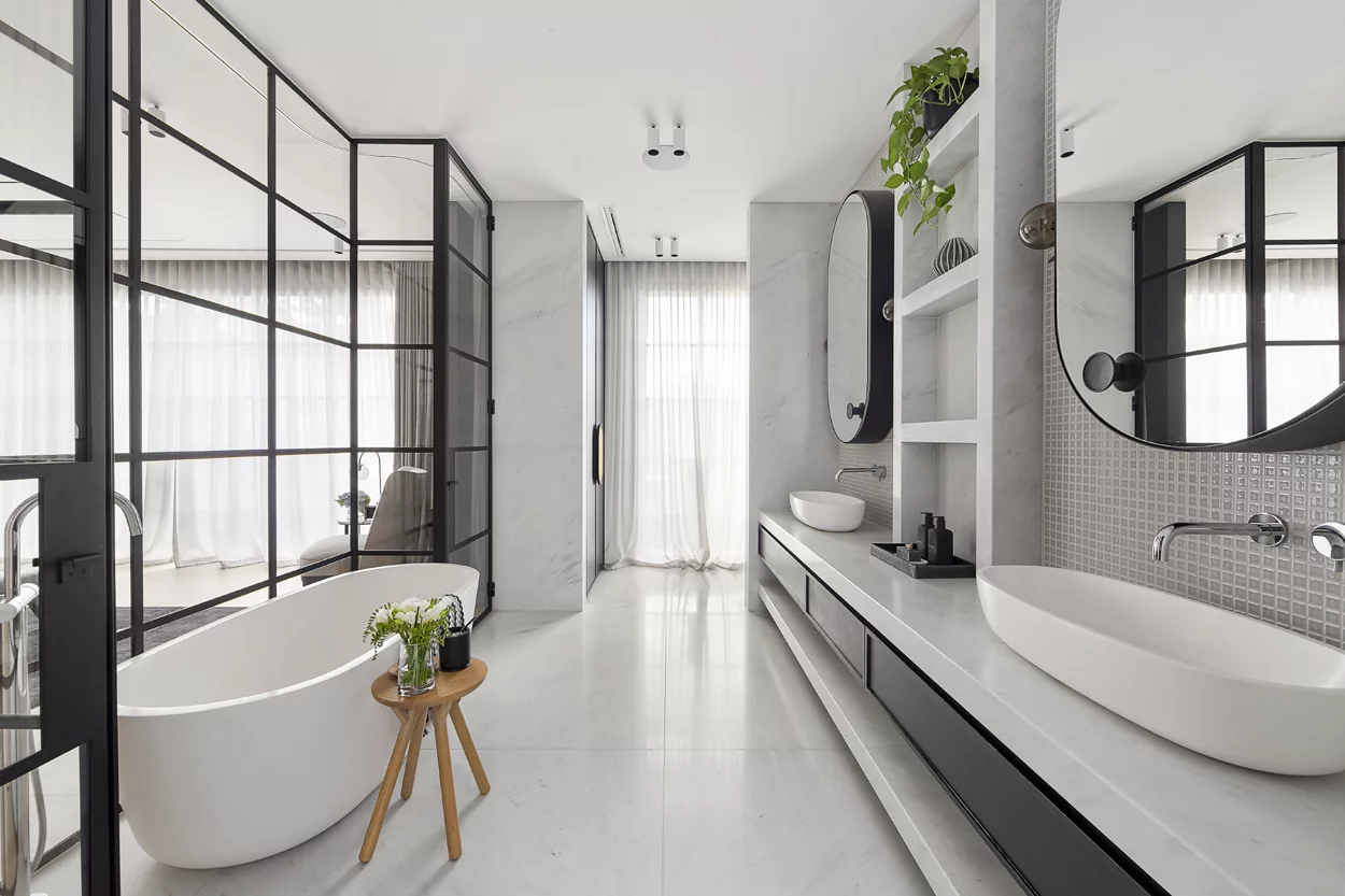 A bathroom with a tub, sink and mirror.